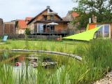 Die "Quelle" liegt im Parterre des Hauses. Hier vom Schwimmteich aus gut zu sehen die große Hochterrasse der Quelle. Rechts im Bild übrigens die Gartensauna!